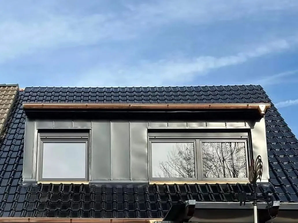 Neue Flachdachgaube mit anthrazitfarbener Stehfalzverkleidung, glasierten Tondachziegeln und Kupferdachrinnen