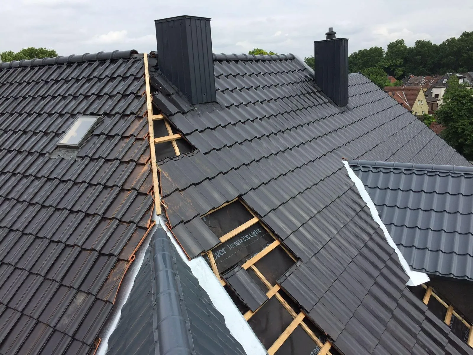 Dachsanierung mit schwarzen Tondachziegeln, neuer Kehle und blechverkleideten Schornsteinen