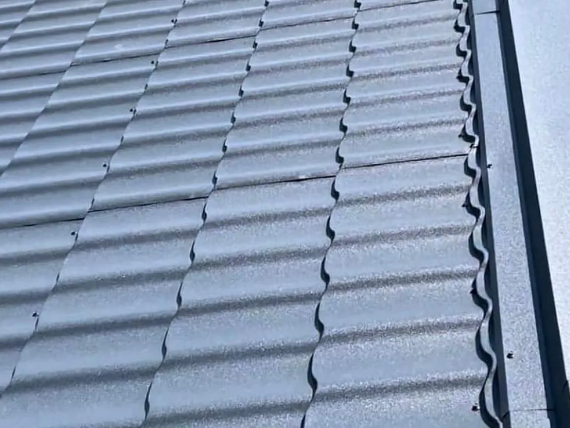 Dacheindeckung mit anthrazitfarbenen Metalldachpfannen und Ortgangblech
