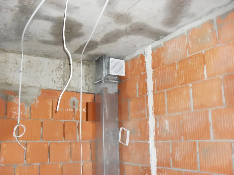 Innenraum im Rohbau mit Ziegelwänden und Installationen